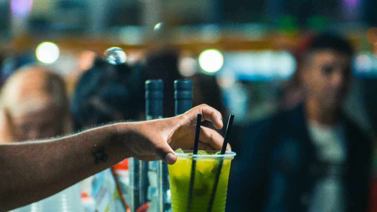 A person holding a green drink in a glass. — a Sleep Finally guide to The Drink That Stands In: Replacing the Evening Glass.