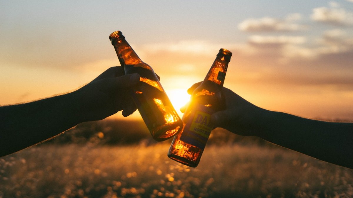 Photography of person holding glass bottles during sunset. — a Sleep Finally guide to The Loan and Its Rate: What Alcohol Borrows From Sleep.