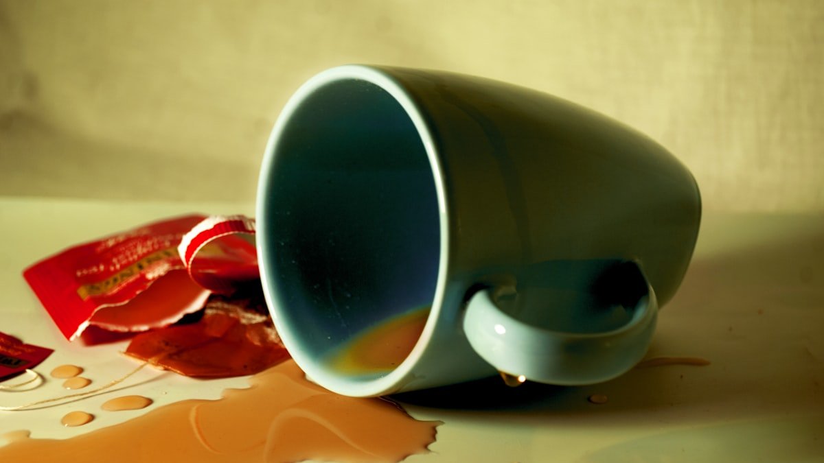 A coffee cup spilled on a table. — a Sleep Finally guide to The Nightcap Myth: Why That Drink Backfires by 2am.