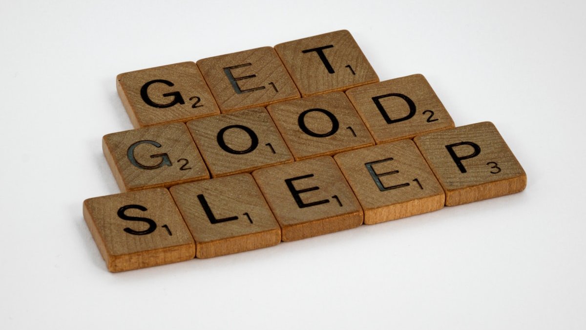 Brown wooden letter blocks on white surface. — a Sleep Finally guide to The Sleep Effort Paradox, Explained.