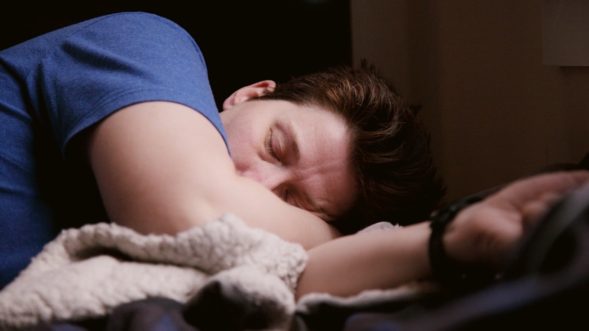 Man in blue shirt sleeping. — a Sleep Finally guide to The Two-Hour Rule for Weekend Sleep-Ins.