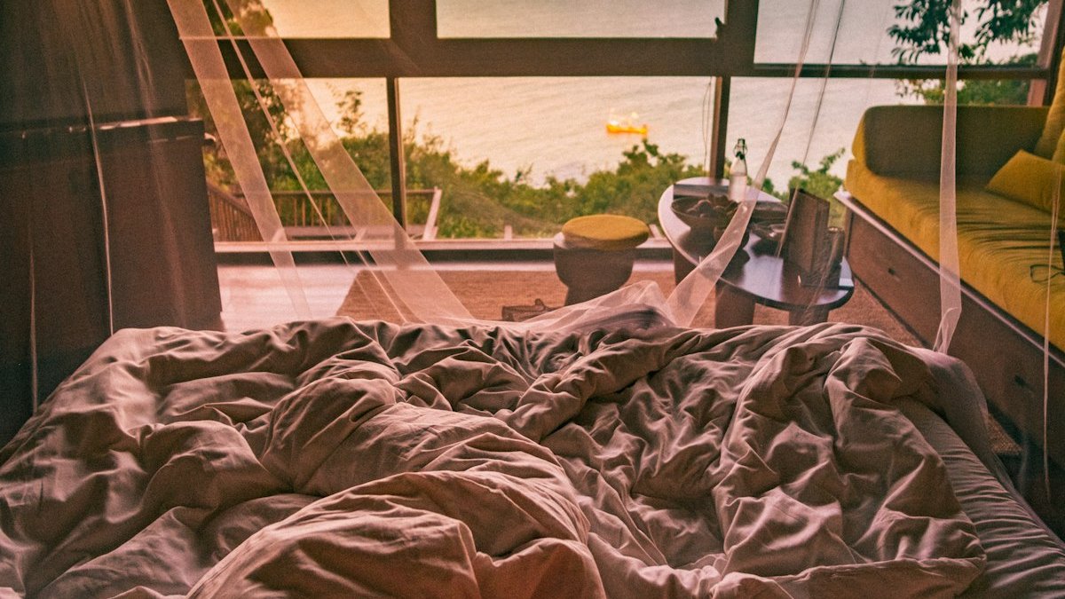 Person lying on bed near window. — a Sleep Finally guide to Vacation Insomnia: Why You Can't Switch Off on Trips.
