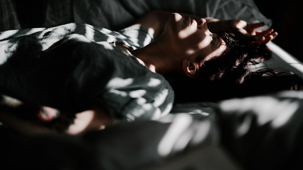 A person laying in bed with their head on a pillow. — a Sleep Finally guide to Waking Up at the Same Time Every Night: Why 3:17.