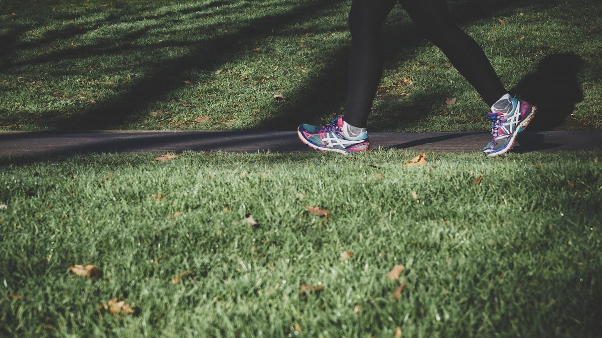 Shallow focus photography of person walking on road between grass. — a Sleep Finally guide to Walking for Better Sleep: The Tool Nobody Sells.