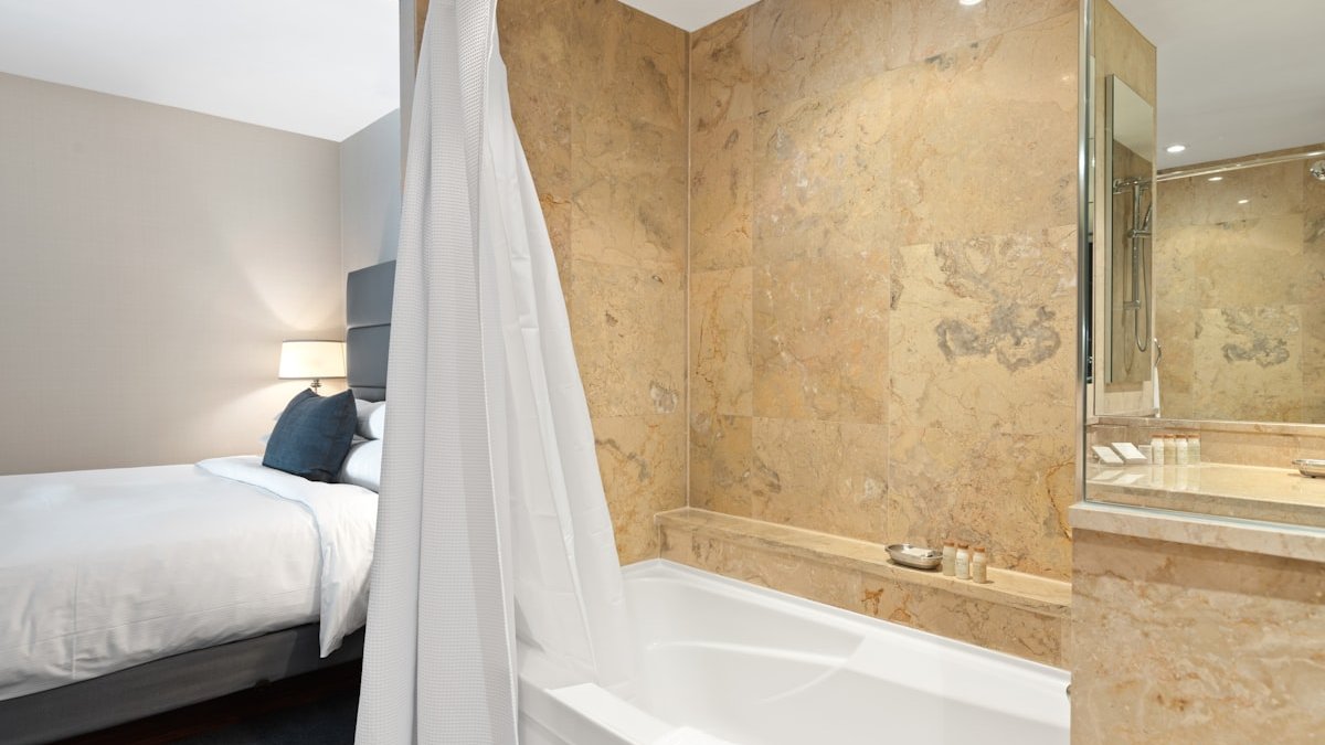 White bathtub near brown wall tiles. — a Sleep Finally guide to Warm Bath or Shower Before Bed: Which Helps More.