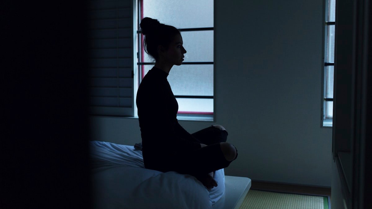 Woman sitting on bed. — a Sleep Finally guide to What to Tell Your Doctor About Insomnia.