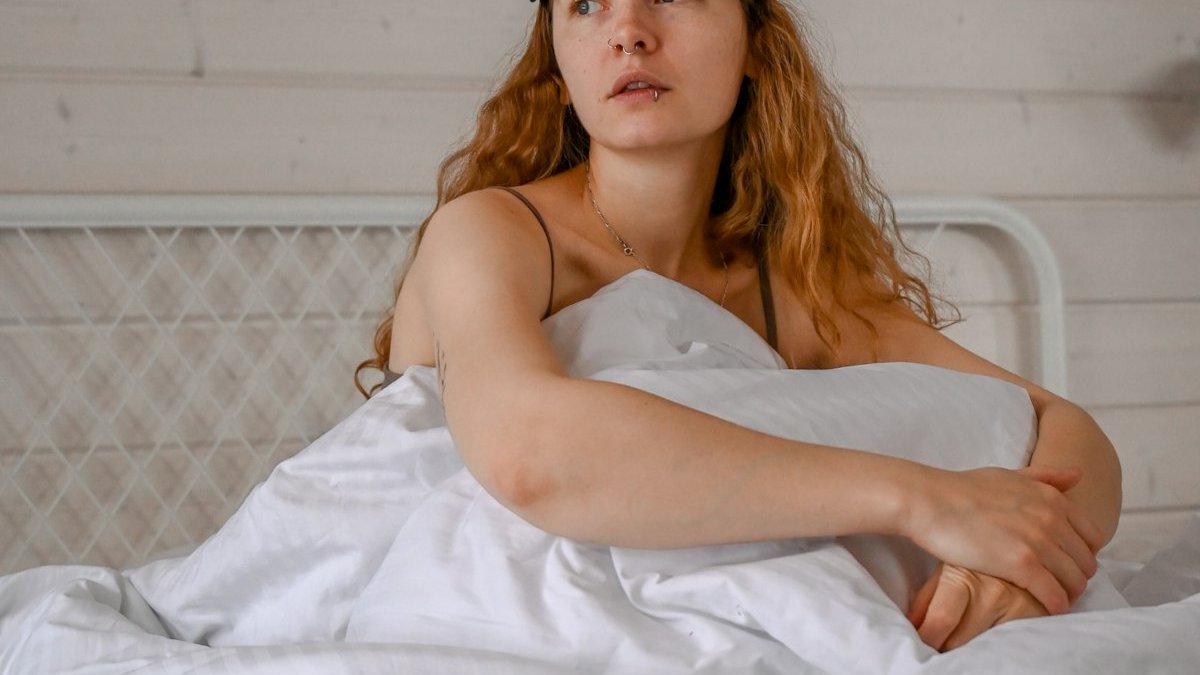A woman lying on a bed. — a Sleep Finally guide to When Do Menopause Night Sweats Stop? An Honest Timeline.