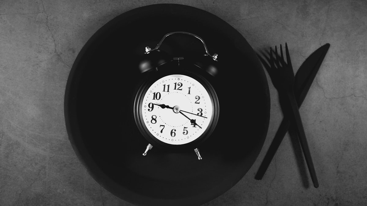 Alarm clock on a plate with cutlery. — a Sleep Finally guide to When to Eat on a Night Shift: Timing That Helps.