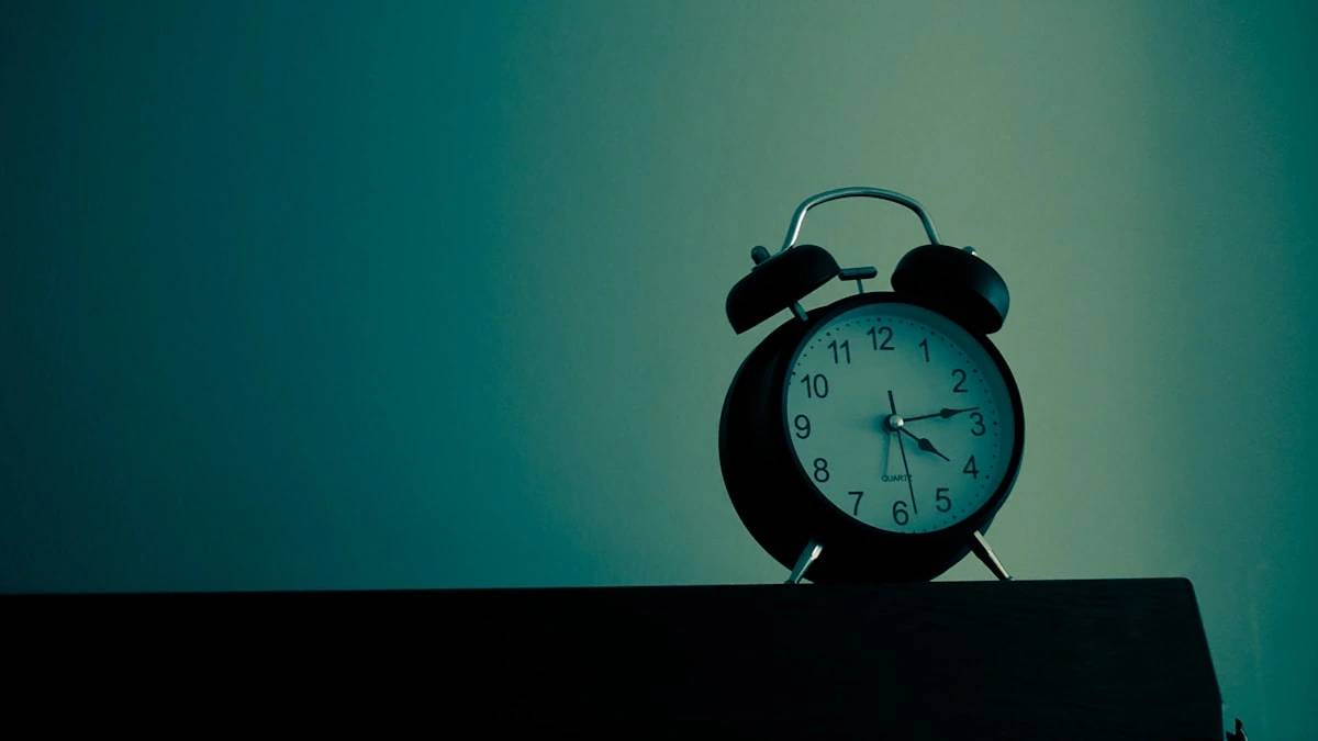 black and white analog alarm clock at 10 10 — a Sleep, Finally guide to Why Clock-Watching Makes Insomnia Worse