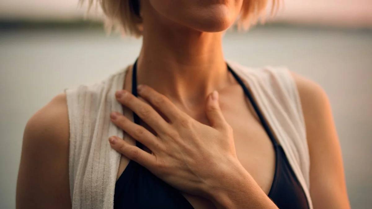 woman in white vest and black bikini with hand on chest — a Sleep, Finally guide to Deep Breathing Anxiety: When Trying Harder Backfires