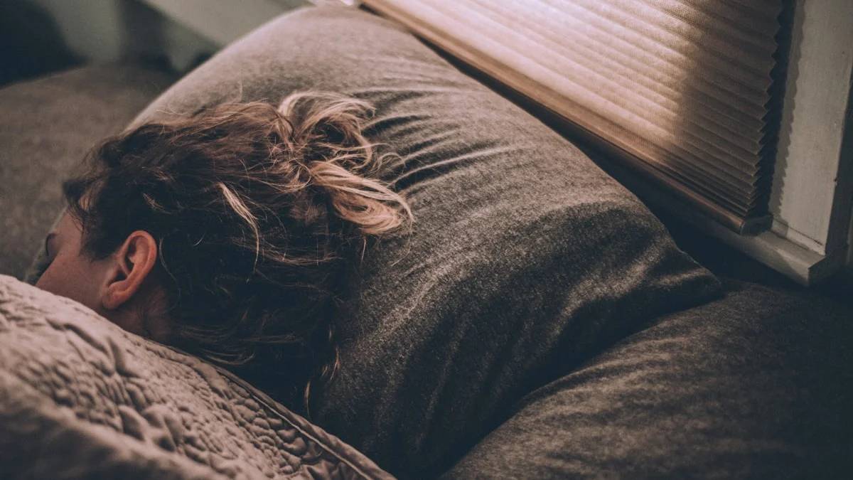 woman sleeping on bed under blankets — a Sleep, Finally guide to Why Is Perimenopause Ruining My Sleep?