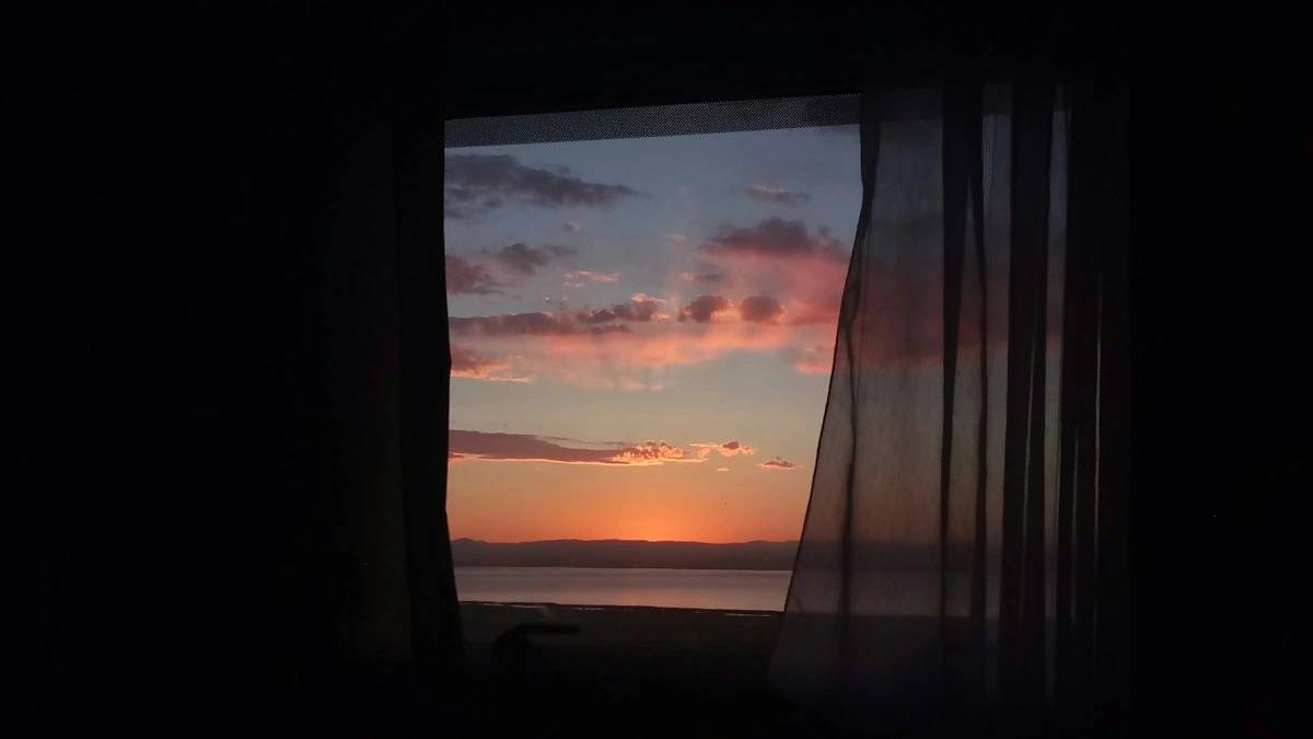 window curtain with view of sea water during sunset — a Sleep, Finally guide to Why Sunday Night Sleep Is the Worst (and the Fix)