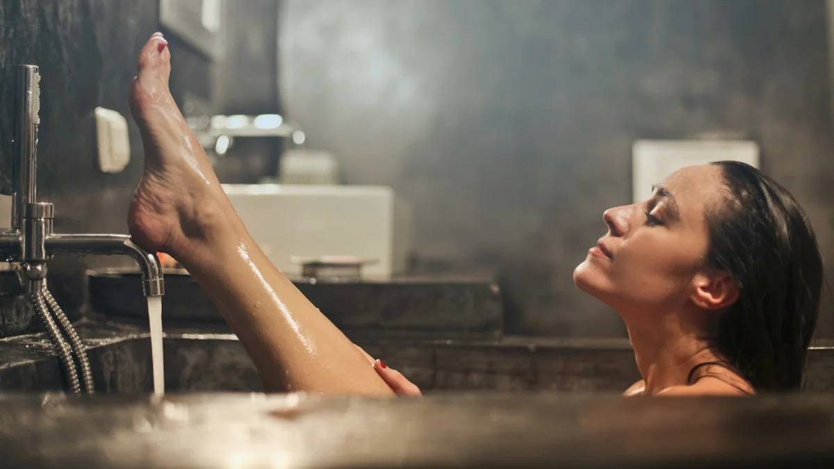 woman lifting his leg — a Sleep, Finally guide to Why Warm Baths Make You Sleepy (The Real Reason)